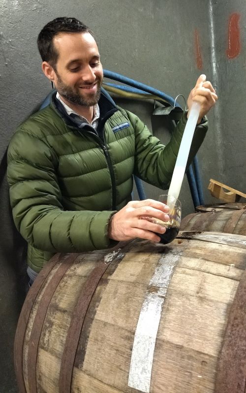 a brewer pulls a sample of beer from a barrel in the cape winelands in south africa