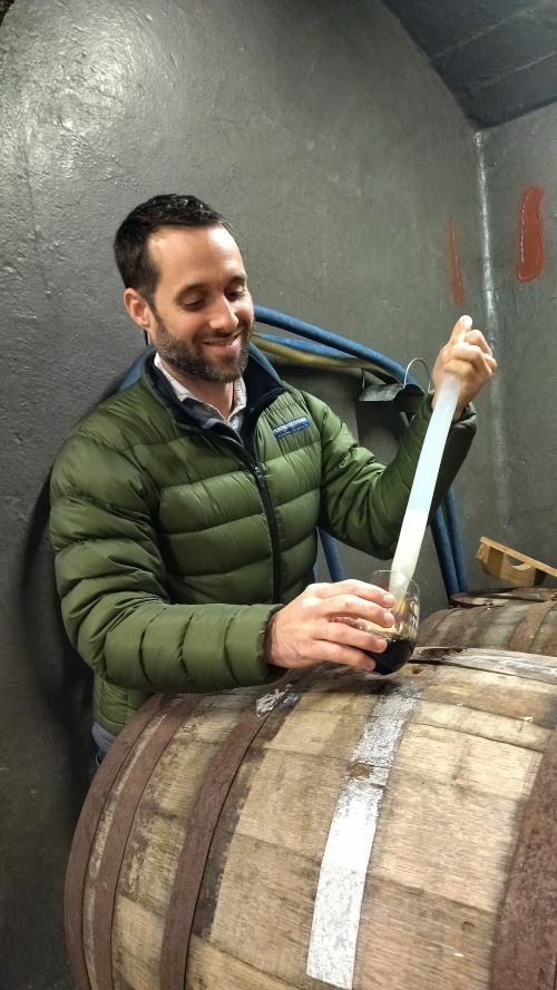 a brewer takes a sample of the strongest beer in africa from the barrel